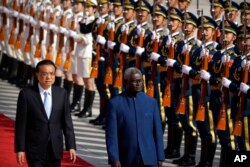 FILE - Chinese Premier Li Keqiang, left, and Solomon Islands Prime Minister Manasseh Sogavare review an honor guard during a welcome ceremony at the Great Hall of the People in Beijing, on Oct. 9, 2019.