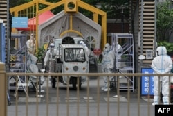 Security personnel wearing personal protective equipment (PPE) man the entrance to a residential area on lockdown due to the recent Covid-19 coronavirus outbreaks in Beijing on May 10, 2022. (Photo by Noel Celis / AFP)