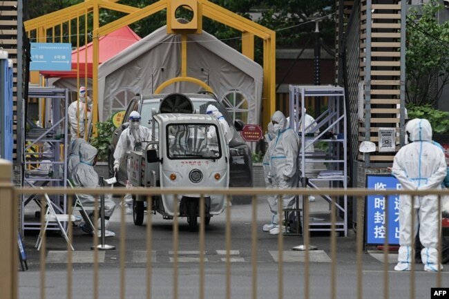 Security personnel wearing personal protective equipment (PPE) man the entrance to a residential area on lockdown due to the recent Covid-19 coronavirus outbreaks in Beijing on May 10, 2022. (Photo by Noel Celis / AFP)