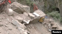 A crane removes debris from around a trapped vehicle after the collapse of a tunnel under construction in Ramban, Jammu and Kashmir, May 20, 2022, in this still image obtained from a video.