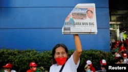2022年5月10日，菲律宾总统候选人费迪南德·“邦邦”·小马科斯的支持者举着一份标题是小马科斯获胜的报纸。（路透社）