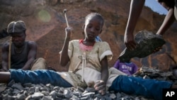 FILE - Irene Wanzila, 10, works breaking rocks with a hammer at the Kayole quarry in Nairobi, Kenya, Sept. 29, 2020, along with her younger brother, older sister and mother.