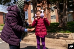 FILE - Asenat Safi, 4, reacts to a coin that her grandmother Fawzi Safi, 71, found outside the family's apartment in Alexandria, Va., April 11, 2022. The family was evacuated from Afghanistan and is trying to make a new life in the U.S., while in immigration limbo.