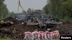 Ukrainian service members ride on top of a military vehicle, amid Russia's invasion of Ukraine, on the road from Bakhmut to Kostyantynivka, in the Donetsk region, Ukraine, May 29, 2022.