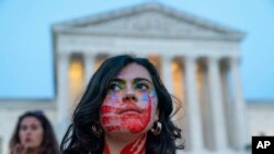 Une femme de Virginie porte des empreintes de mains rouges pour représenter la violence à l'égard des femmes, lors d'une manifestation devant la Cour suprême des États-Unis, le mardi 3 mai 2022, à Washington.