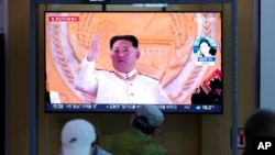 People watch a TV screen showing a news program reporting about North Korea's missile launch with file footage of North Korean leader Kim Jong Un at a train station in Seoul, South Korea, May 12, 2022.