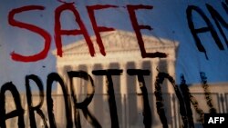The Supreme Court is seen through a banner reading "Safe Abortion" in Washington on May 10, 2022. 
