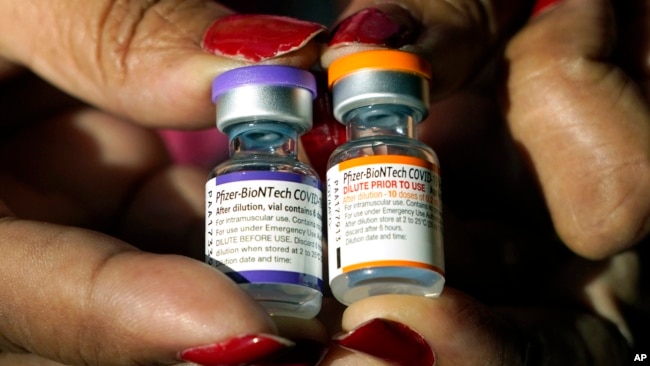 FILE - A nurse holds a vial of the Pfizer COVID-19 vaccine for children ages 5 to 11, right, and a vial of the vaccine for adults, which has a different colored label, at a vaccination station in Jackson, Miss., Tuesday, Feb. 8, 2022. (AP Photo/Rogelio V. Solis, File)