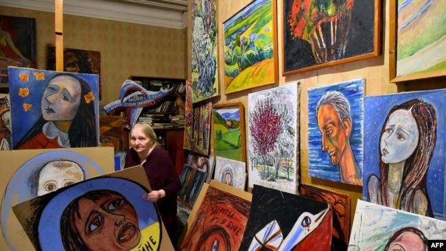 Russian artist Yelena Osipova, 76, speaks to AFP near anti-war placards she made to protest the conflict in Ukraine, in her home in Saint Petersburg on May 8, 2022.