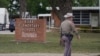 Un officier marche devant la Robb Elementary School à Uvalde, après la fusillade d'un jeune homme ayant tué des enfants et des enseignants dans une école primaire du Texas le 24 mai 2022. (Photo AFP Allison Dinner)