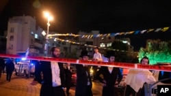 Ultra-orthodox Jews stand behind police tape after a stabbing attack in the town of Elad, Israel, May 5, 2022. 