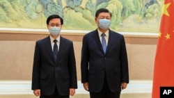 In this photo released by Xinhua News Agency, Chinese President Xi Jinping, right, and Hong Kong Chief Executive-elect John Lee pose for photo before their meeting in Beijing, May 30, 2022.