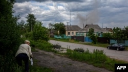 A woman runs to cover from shelling in a recently retaken village north of Kharkiv, eastern Ukraine, May 25, 2022, amid the Russian invasion of Ukraine.