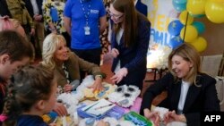 La primera dama de EEUU, Jill Biden (izq.), y la esposa del presidente de Ucrania, Olena Zelenska, se unen a un grupo de niños que fabrican osos de papel de seda para regalar por el Día de la Madre en la Escuela 6, una escuela pública que acogió a estudiantes desplazados en Uzhhorod, Ucrania, el 8 de mayo de 2022.