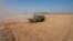 A combine harvests wheat crops in Yousifiyah, Iraq, May. 24, 2022. Iraqi farmers say they are paying the price for a government decision to cut irrigation for agricultural areas by 50% due to severe water shortages.