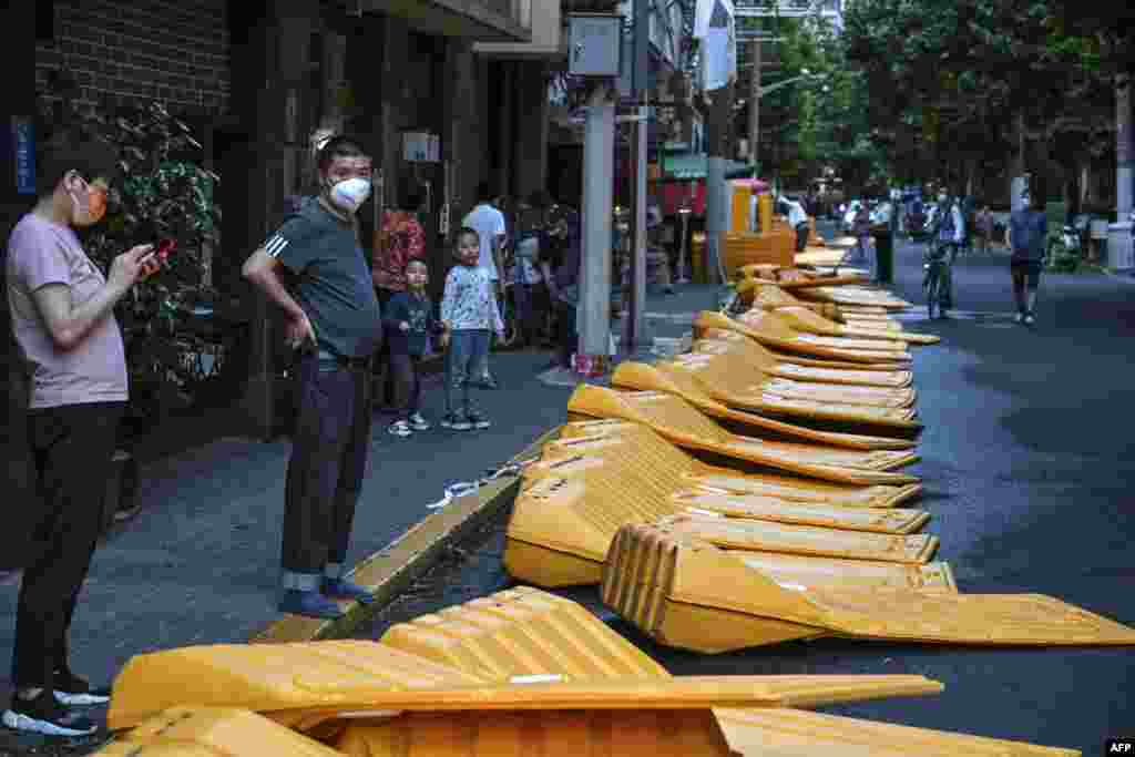 People stand next to barriers taken down earlier in the afternoon in the Jing&#39; an district of Shanghai, China, as the city prepares to lift more curbs after two months of heavy-handed restrictions.