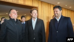 This photo from Brazil's Ministry of Communication shows President Jair Bolsonaro, left; his communication minister, Fabio Faria, right; and SpaceX CEO Elon Musk at the Conecta Amazonia in Porto Feliz, Sao Paulo state, Brazil, May 20, 2022.