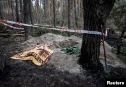 Telo žene civila, Jaroslave (43), pokriveno ćebetom u blizini iskopanog groba, koju su prema svedočenjima ubili ruski vojnici, tokom ruske invazije na Ukrajinu, u selu Motizin, u oblasti Kijeva, 4. aprila 2022.