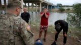 Three migrants from Cuba stand in front of a National Guardsman after crossing the Rio Grande river in Eagle Pass, Texas, May 22, 2022.