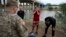 Three migrants from Cuba stand in front of a National Guardsman after crossing the Rio Grande river in Eagle Pass, Texas, May 22, 2022.