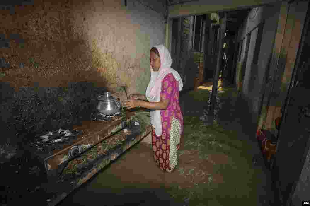 Seorang perempuan memasak di luar rumahnya di lorong yang tergenang banjir setelah hujan deras melanda kota Sylhet, Bangladesh. (Foto: AFP)