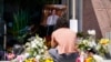 Gabe Kipers, a neighbor of church shooting victim Dr. John Cheng, kneels at a memorial for him outside his office building on May 17, 2022, in Aliso Viejo, Calif. 