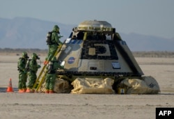 In this handout photo, NASA, Boeing and NASA teams work around the Boeing CST-100 Starliner spacecraft after it touched down at White Sands Missile Rangs Space Harbor, May 25, 2022, in New Mexico.  (Photo by Bill Ingalls/NASA/AFP)