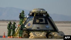 FILE - In this handout image courtesy of NASA, Boeing and NASA teams work around Boeing's CST-100 Starliner spacecraft after it landed at White Sands Missile Range's Space Harbor, May 25, 2022, in New Mexico.