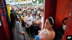 A woman waits for a polling center to open with her baby on May 9, 2022, in Quezon City, Philippines. Filipinos began voting for a new president on Monday with the son of an ousted dictator and a champion of reforms and human rights as top contenders in a
