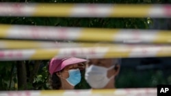지난 15일 중국 베이징 주민들이 마스크를 쓴 채 차단 테이프 뒤에 서 있다. (자료사진)