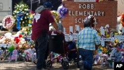 People pay their respects at a memorial outside Robb Elementary School in Uvalde, Texas, May 28, 2022.