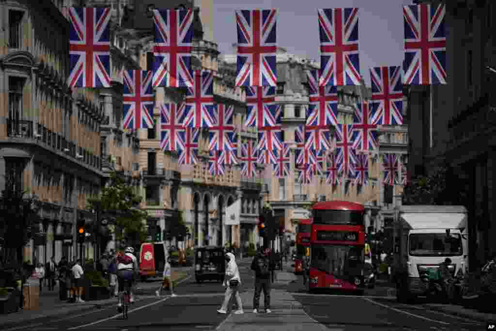 People cross the Regent Street shopping district with Union flags hanging over it to mark the upcoming Platinum Jubilee of the 70 year reign of Britain&#39;s Queen Elizabeth II, in London.