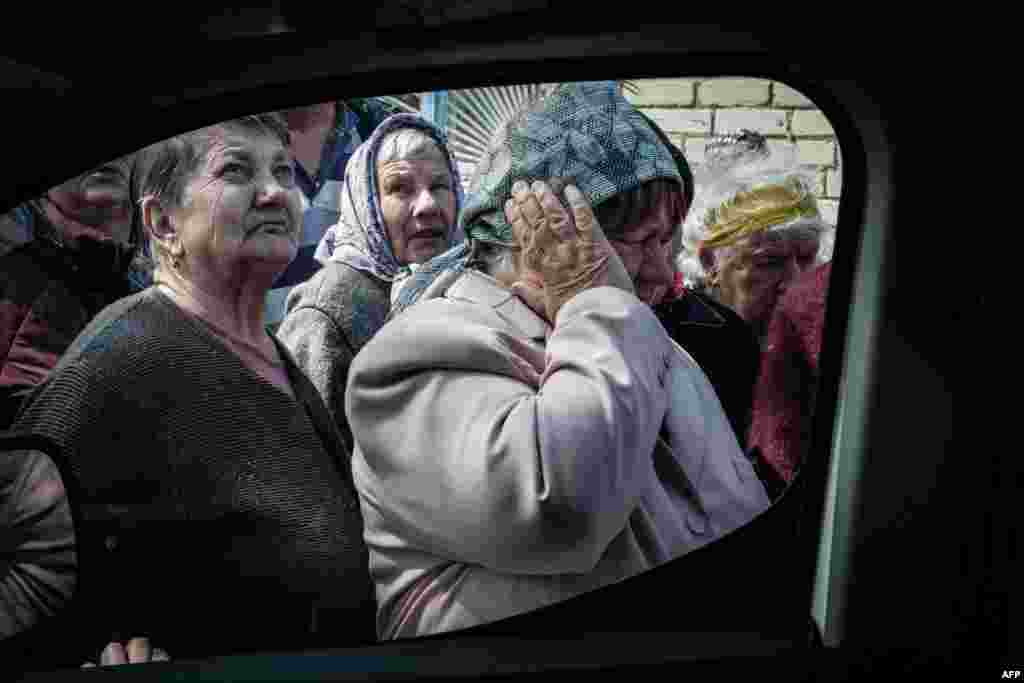 A woman covers her ears from the sound of mortar fire as people queue to collect pensions from a postal delivery van that reached the frontline despite the ongoing conflict in Mayaky, eastern Ukraine, amid the Russian invasion of Ukraine.