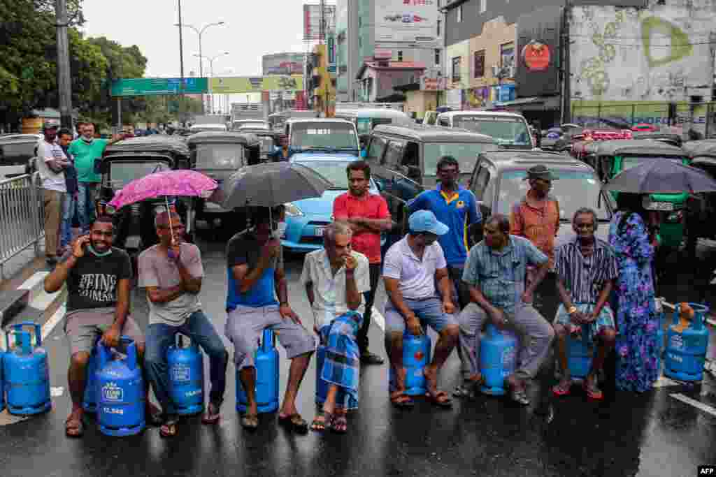 People sit on empty Liquified Gas Cylinders as they block a road to protest a shortage of fuel and cooking gas in Colombo, Sri Lanka. 