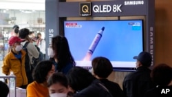 People watch a TV showing a file image of North Korea's missile launch during a news program at the Seoul Railway Station in Seoul, South Korea, May 7, 2022. 