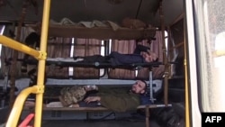 This screen grab obtained from a handout video by the Russian Defense Ministry, May 17, 2022, shows Ukrainian service members lying on stretchers in a vehicle after leaving the Azovstal steel plant in Mariupol. (Photo by Handout / Russian Defense Ministry / AFP) 