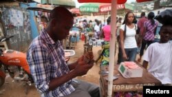 FILE - Alpha Abdulai Barrie, a 22-year-old agent for telecoms firm Africell, sits at his stall at Lumley Junction in Sierra Leone's capital Freetown, Dec. 13, 2012.