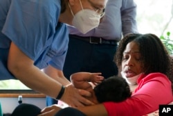 Capri Isidoro is handed her one-month-old baby Charlotte, as Ann Faust, an International Board Certified Lactation Consultant, weighed the baby after Isidoro breastfed her, as part of a lactation consultation in Columbia, Md., May 23, 2022.