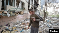 FILE - A local man walks on debris of a residential building damaged by a military strike, as Russia's attack on Ukraine continues, in Sievierodonetsk, Luhansk region, Ukraine. April 16, 2022. 