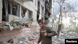 FILE - A local man walks on debris of a residential building damaged by a military strike, as Russia's attack on Ukraine continues, in Sievierodonetsk, Luhansk region, Ukraine April 16, 2022.