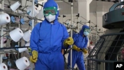 18일 북한 평양의 한 공장 직원들이 신종 코로나바이러스 방역을 위해 생산 시설을 소독하고 있다.