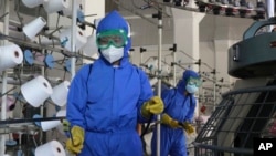 Employees of Songyo Knitwear Factory in Songyo district disinfect the work floor in Pyongyang, North Korea, May 18, 2022, after Kim Jong Un said his party would treat the country's outbreak under the state emergency. 