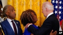 President Joe Biden hugs Tamika Palmer, mother of Breonna Taylor, as the Reverend Al Sharpton watches after Biden signed an executive order on police accountability at the White House, May 25, 2022, in Washington. Taylor, a Black medical worker, was killed in a police raid.
