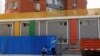 Workers wearing personal protective equipment (PPE), install a barricade around a residential area under lockdown while a resident looks out from a window, amid the coronavirus disease (COVID-19) outbreak in Beijing, China, May 4, 2022.