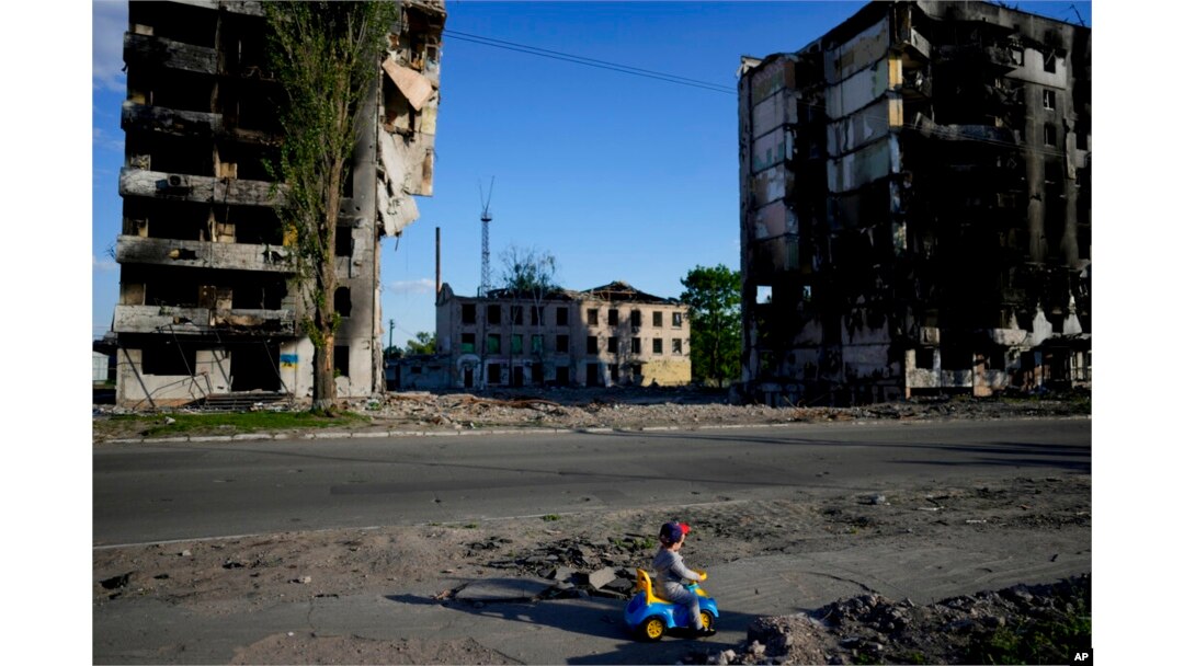 Seorang anak laki-laki bermain di depan rumah yang hancur akibat penembakan di Borodyanka, Ukraina, 24 Mei 2022. (Foto: AP)