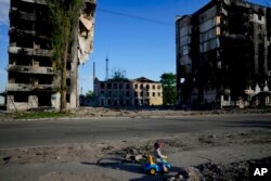 Seorang anak laki-laki bermain di depan rumah yang hancur akibat penembakan di Borodyanka, Ukraina, 24 Mei 2022. (Foto: AP)