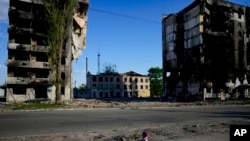 A boy plays in front of houses ruined by shelling in Borodyanka, Ukraine, May 24, 2022. 