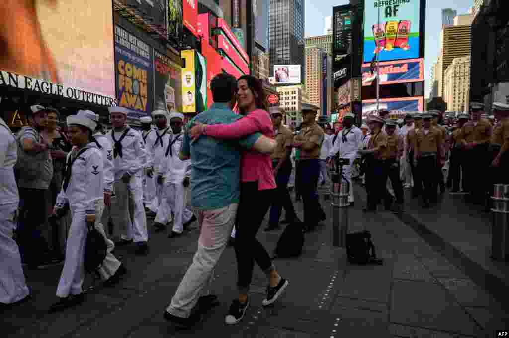 U.S. servicemembers walk past a couple dancing in Times Square, as part of 'Fleet Week' celebrations in New York, May 25, 2022.