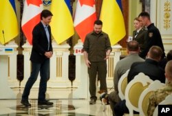 Presiden Ukraina Volodymyr Zelenskyy, tengah, dan Perdana Menteri Kanada Justin Trudeau, menghadiri upacara penghargaan untuk pencari ranjau Ukraina dan anjing legendarisnya Patron di Kyiv, Ukraina, 8 Mei 2022. (Foto: AP)