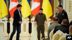 El presidente ucraniano, Volodymyr Zelenskyy, centro, y el primer ministro canadiense, Justin Trudeau, asisten a una ceremonia de premiación para un zapador ucraniano y su legendario perro Patrón en Kiev, Ucrania, el 8 de mayo de 2022.